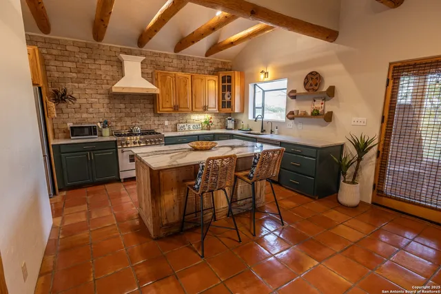 a kitchen with stainless steel appliances kitchen island granite countertop a sink and a refrigerator