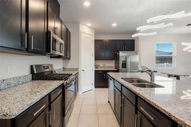 a kitchen with granite countertop stainless steel appliances a sink stove and refrigerator