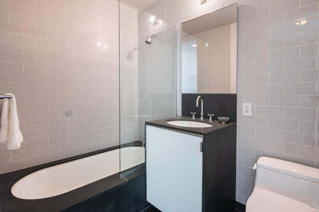 240 Park Avenue South, Unit 14B Manhattan, NY 10003 - Photo 11 of 12 a bathroom with a sink a toilet a mirror and shower
