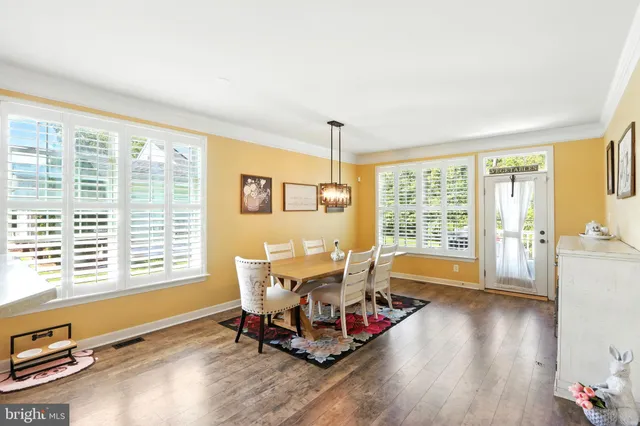 a living room with dining table chairs and wooden floor