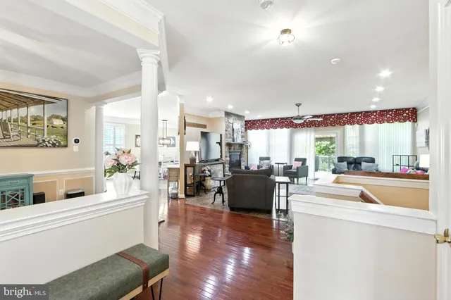 a room with stainless steel appliances kitchen island granite countertop a refrigerator a sink dishwasher a dining table and chairs with wooden floor