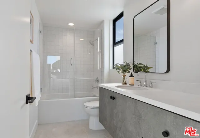 a bathroom with a granite countertop sink a toilet and shower