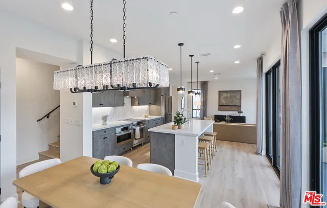 a kitchen with stainless steel appliances kitchen island granite countertop a table chairs and a refrigerator