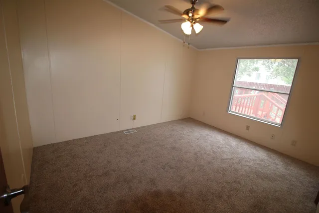 an empty room with a window and a fan