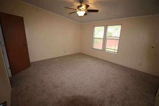 an empty room with a window and a fan
