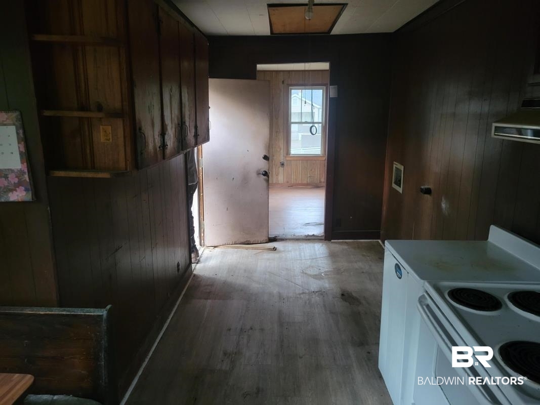 2059 Magnolia Lane Mobile, AL 36605 - Photo 5 of 17 Kitchen featuring light countertops, wood walls, light wood-type flooring, and white electric range