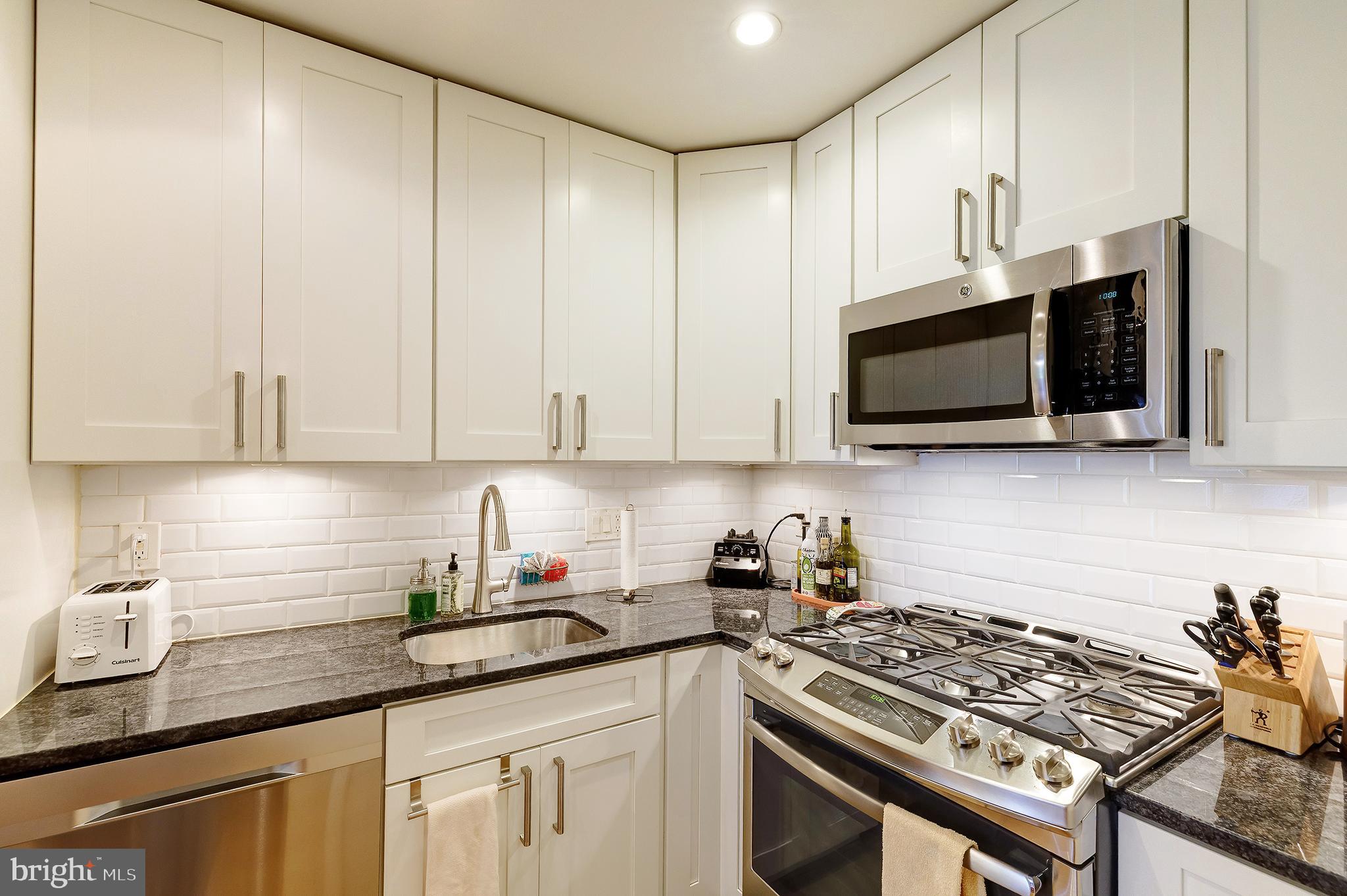 1514 Newton Street Northwest, Unit 301 Washington, DC 20010 - Photo 12 of 30 a kitchen with stainless steel appliances granite countertop white cabinets a stove top oven a sink and dishwasher