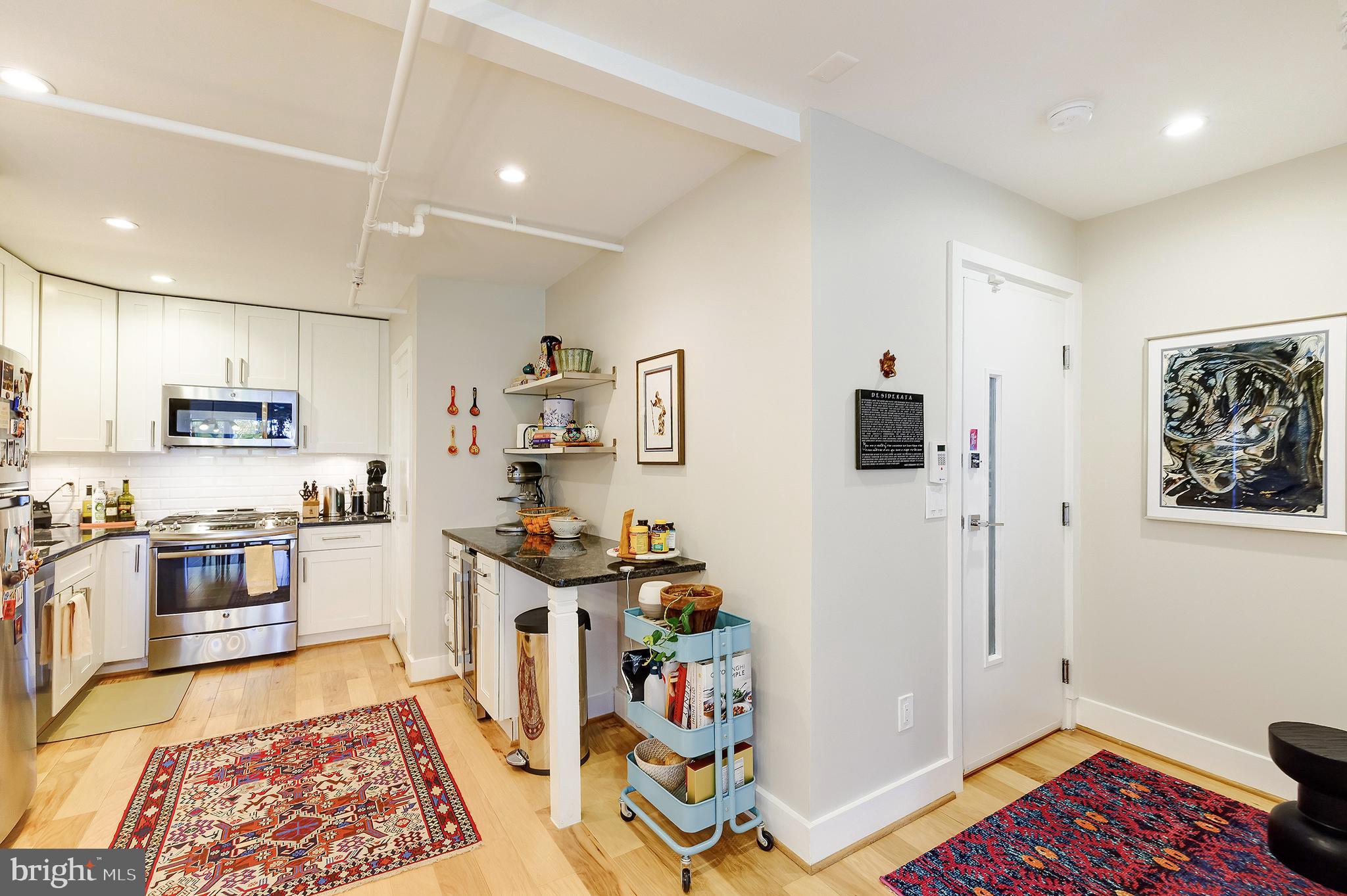 1514 Newton Street Northwest, Unit 301 Washington, DC 20010 - Photo 10 of 30 a kitchen with stainless steel appliances a refrigerator and a wooden floor