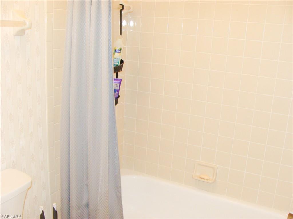 5693 Rattlesnake Hamm Road, Unit A204 Naples, FL 34113 - Photo 13 of 29 a bathroom with a shower curtain