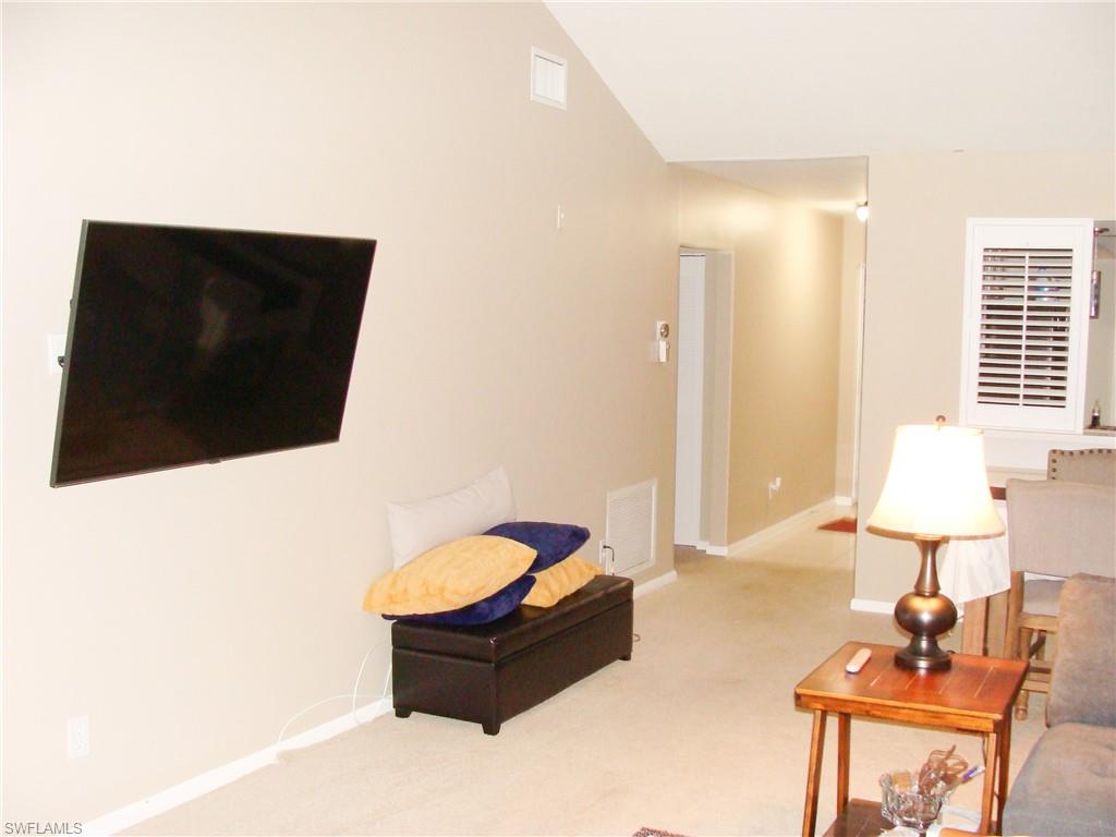 5693 Rattlesnake Hamm Road, Unit A204 Naples, FL 34113 - Photo 6 of 29 a living room with furniture and a flat screen tv