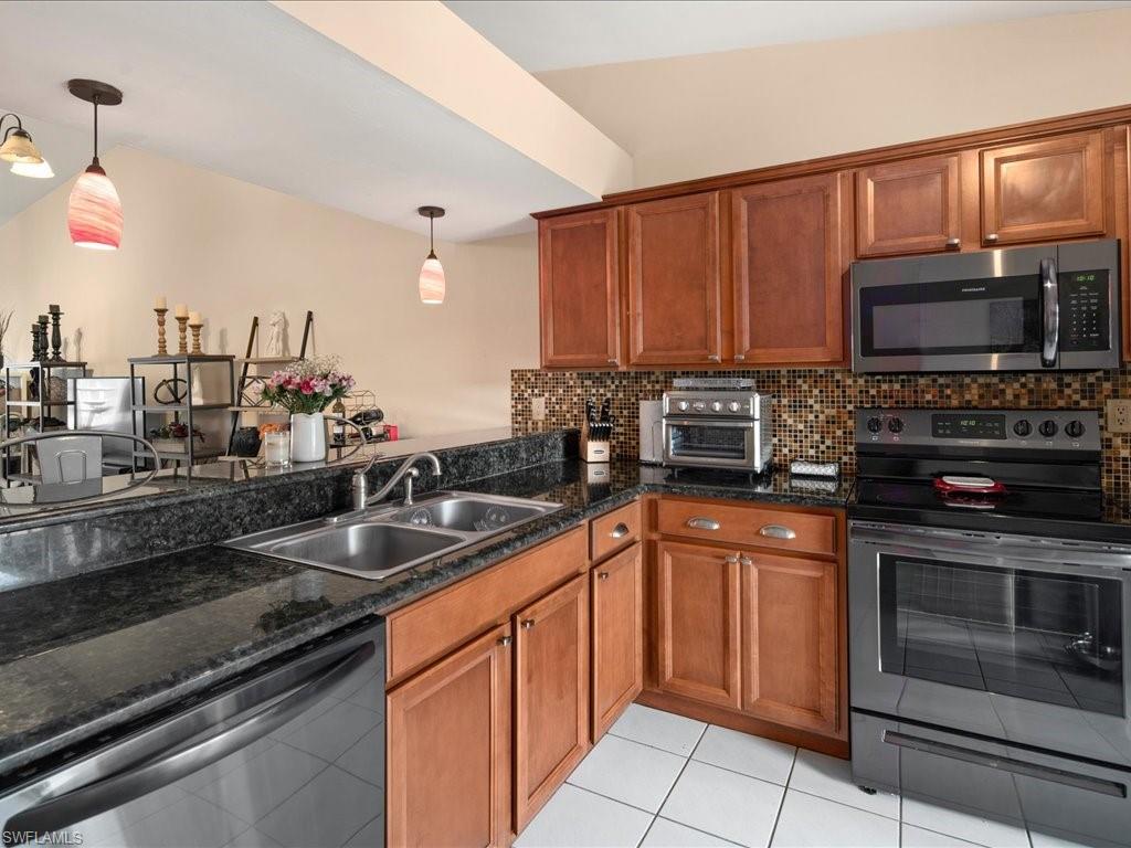 4070 Looking Glass Lane, Unit 3106 Naples, FL 34112 - Photo 17 of 29 a kitchen with stainless steel appliances granite countertop a sink stove and microwave