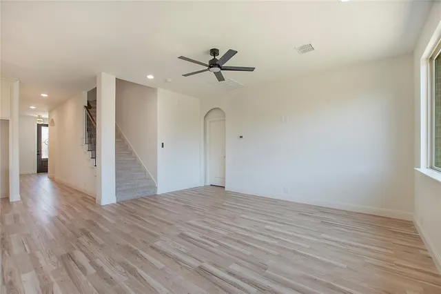 a view of a room with wooden floor a ceiling fan and window