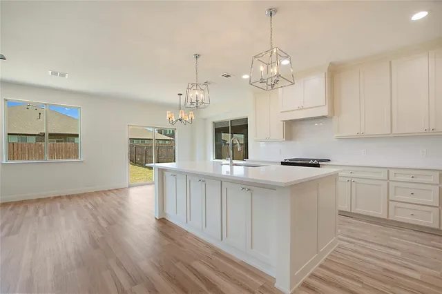 a kitchen with kitchen island granite countertop a sink cabinets and window