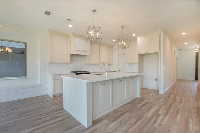 a kitchen with a sink wooden floor stainless steel appliances and cabinets