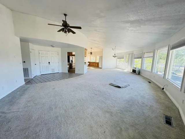 an empty room with a window and a fan