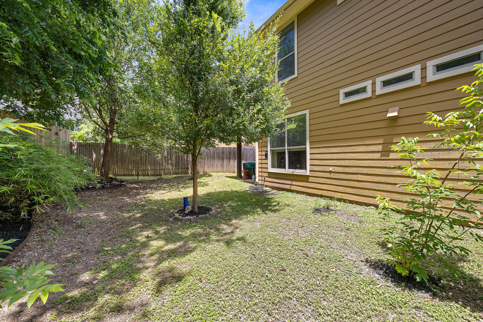 6708 Menchaca Road, Unit 10 Austin, TX 78745 - Photo 28 of 28 Private backyard featuring a slatted wood fence, mature trees, and a ground-level patio
