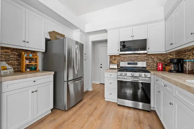 a kitchen with stainless steel appliances white cabinets a stove a refrigerator and a microwave