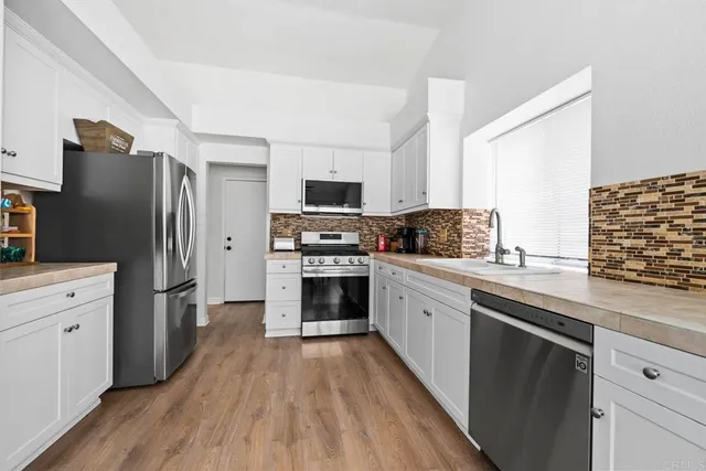 a kitchen with granite countertop a refrigerator stove and sink