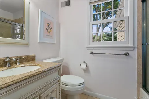 a bathroom with a granite countertop toilet sink and mirror
