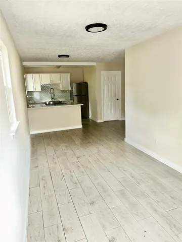 a view of an empty room and kitchen view