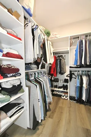 a view of walk in closet with clothes and shoes