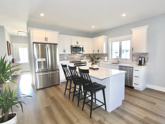 a kitchen with stainless steel appliances a dining table chairs a refrigerator and cabinets