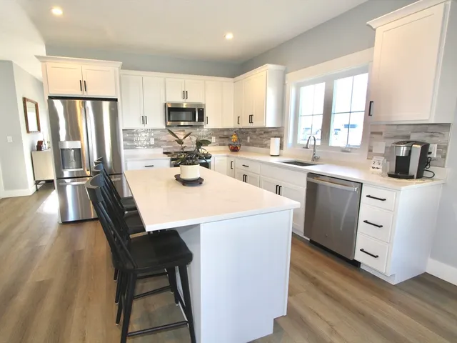 a kitchen with a sink a stove a refrigerator and white cabinets