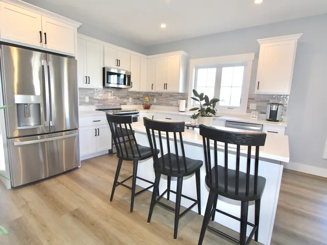 a kitchen with stainless steel appliances granite countertop a dining table chairs refrigerator microwave and cabinets