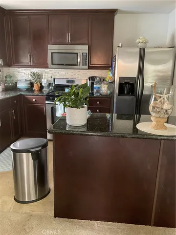 a kitchen with stainless steel appliances a refrigerator a stove a sink a microwave and dining table