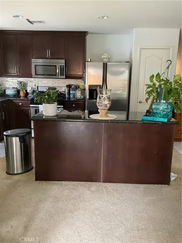 a kitchen with stainless steel appliances granite countertop a refrigerator a stove and a sink