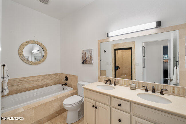 2522 Lake Ridge Shores Circle Reno, NV 89519 - Photo 38 of 50 a bathroom with a toilet a sink a mirror and a bathtub