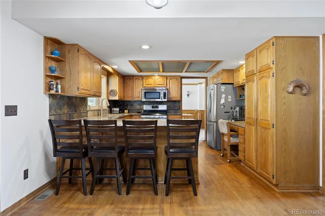 a kitchen with stainless steel appliances granite countertop a stove top oven a sink a dining table and chairs