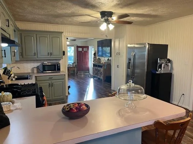 a kitchen with stainless steel appliances granite countertop a refrigerator a stove and a sink with wooden floor