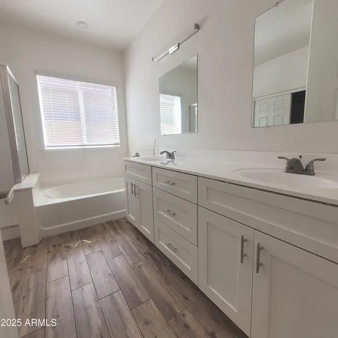 a bathroom with a sink a mirror a bathtub and next to a window