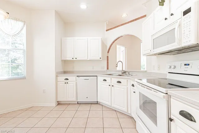 a kitchen with granite countertop white cabinets and window
