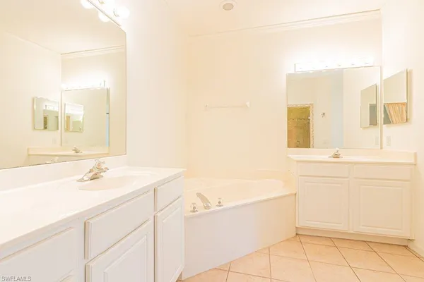 a spacious bathroom with a double vanity sink a mirror and a bathtub