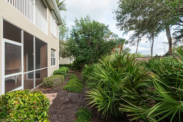 a front view of a house with plants and large trees