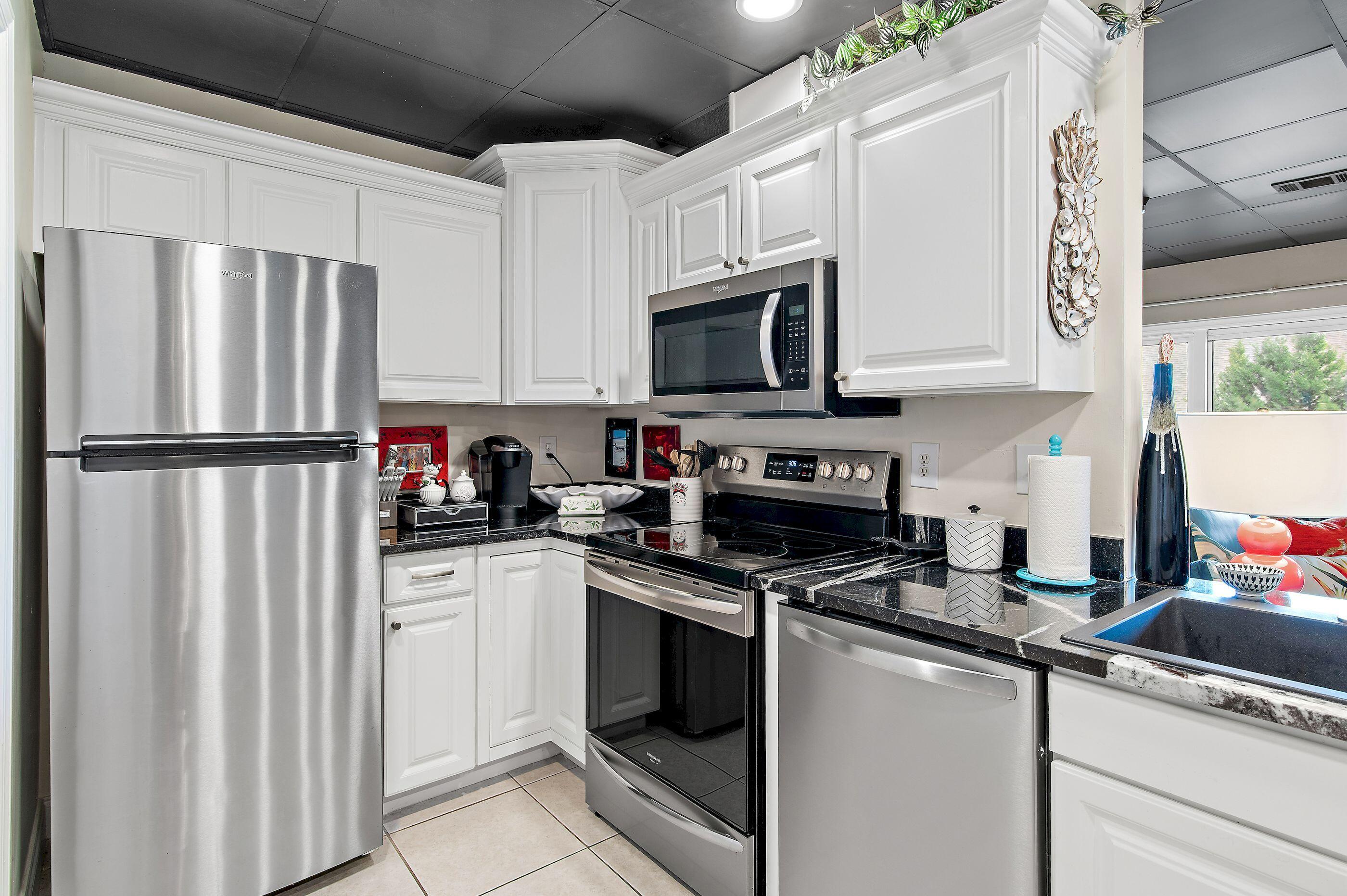 197 Durango Road, Unit 2B Destin, FL 32541 - Photo 8 of 29 a kitchen with granite countertop a refrigerator sink and white cabinets