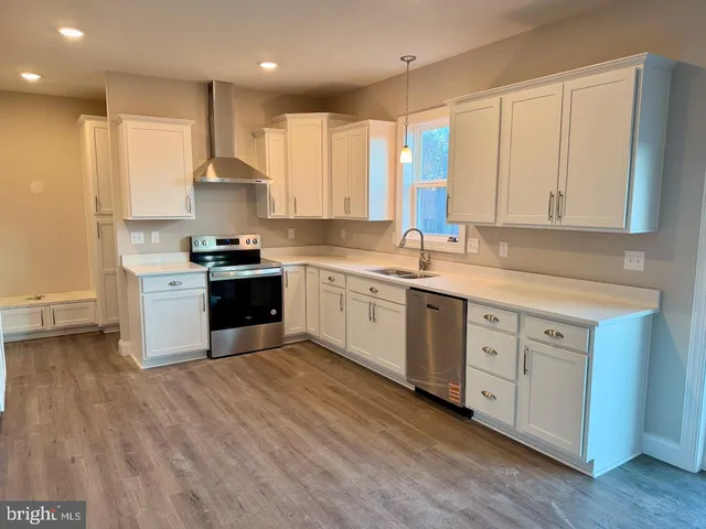 a kitchen with stainless steel appliances granite countertop a stove a sink and white cabinets