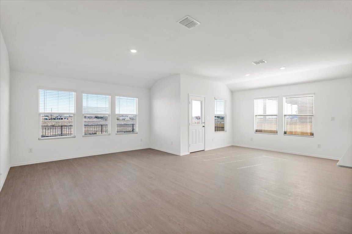 221 Rodney Boat Road Kyle, TX 78640 - Photo 10 of 33 Unfurnished living room with light wood-type flooring, vaulted ceiling, and recessed lighting