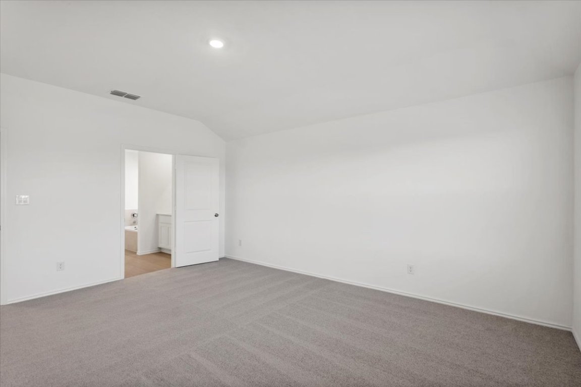 221 Rodney Boat Road Kyle, TX 78640 - Photo 27 of 33 Unfurnished bedroom with light carpet, vaulted ceiling, ensuite bathroom, and recessed lighting