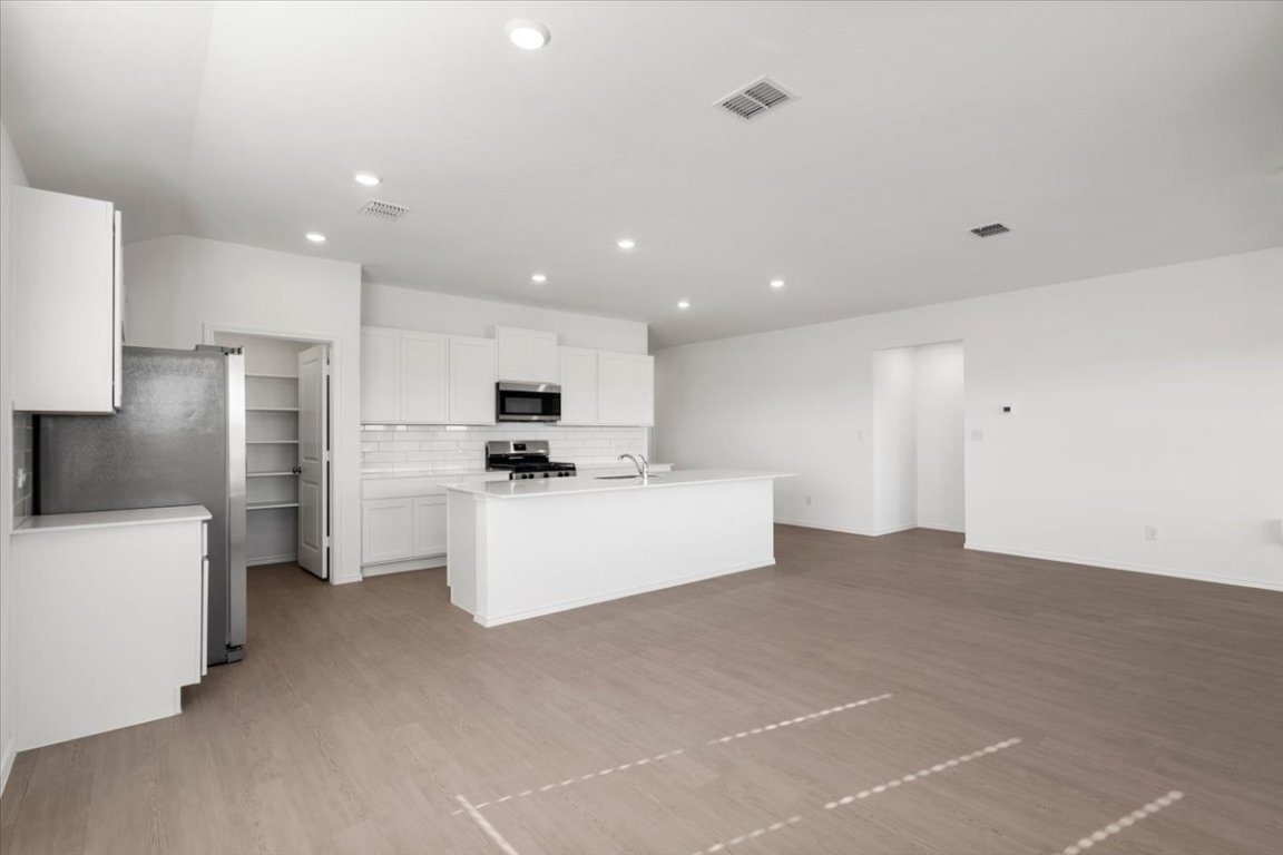 221 Rodney Boat Road Kyle, TX 78640 - Photo 8 of 33 Kitchen featuring tasteful backsplash, appliances with stainless steel finishes, white cabinets, an island with sink, and recessed lighting