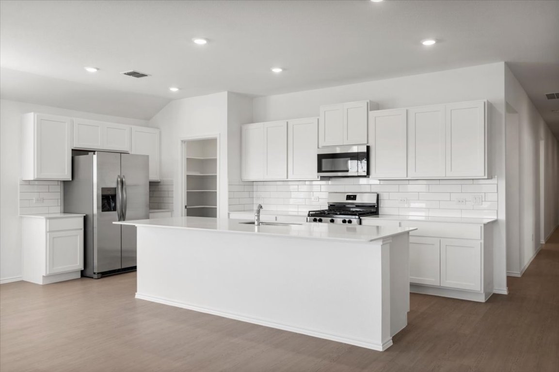 221 Rodney Boat Road Kyle, TX 78640 - Photo 9 of 33 Kitchen featuring white cabinets, stainless steel appliances, decorative backsplash, an island with sink, and recessed lighting