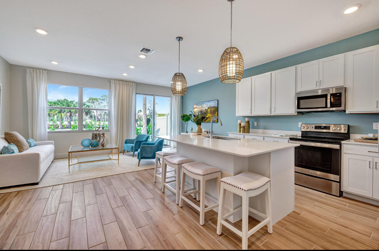 608 Waters Edge Lane, Unit 2202 Port St. Lucie, FL 34983 - Photo 4 of 19 a very nice looking kitchen with granite countertop a stove a sink a microwave and wooden floors