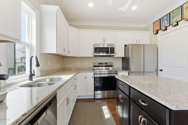 a kitchen with stainless steel appliances granite countertop a sink a stove and a wooden floors