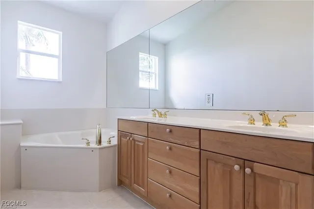 a bathroom with a sink double vanity granite tub and a window
