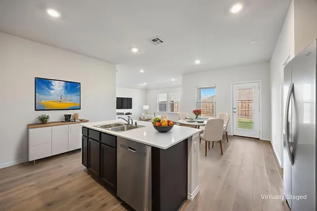 a kitchen with stainless steel appliances granite countertop a table chairs and a refrigerator