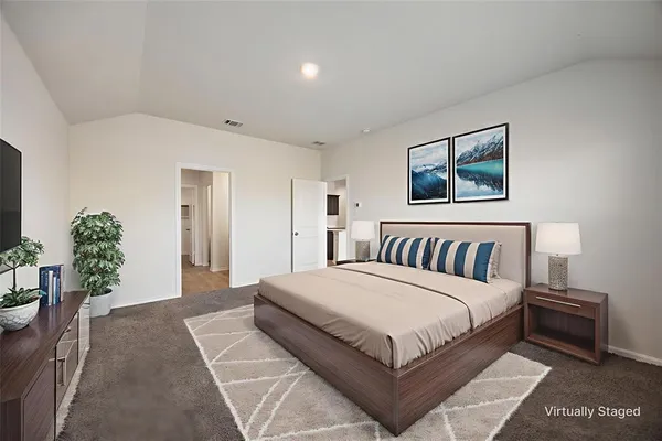 a spacious bedroom with a large bed a rug and potted plant