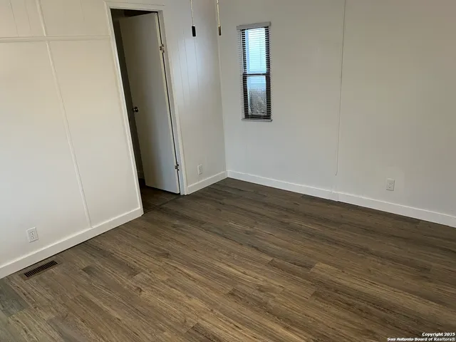 an empty room with wooden floor and entrance