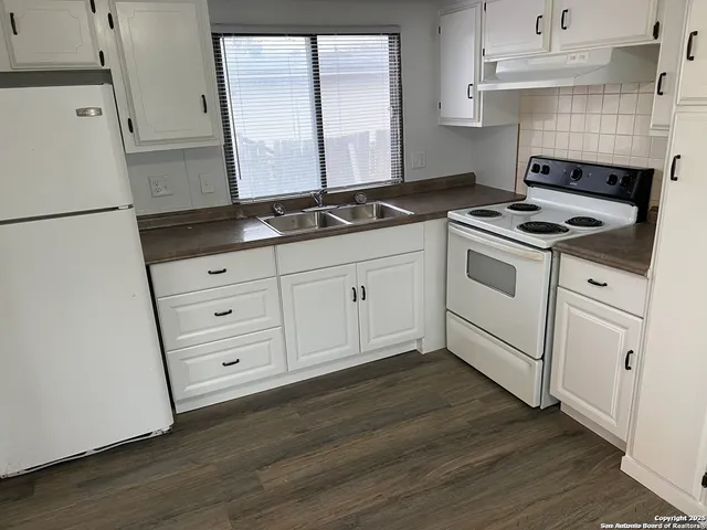a kitchen with granite countertop white cabinets and white appliances